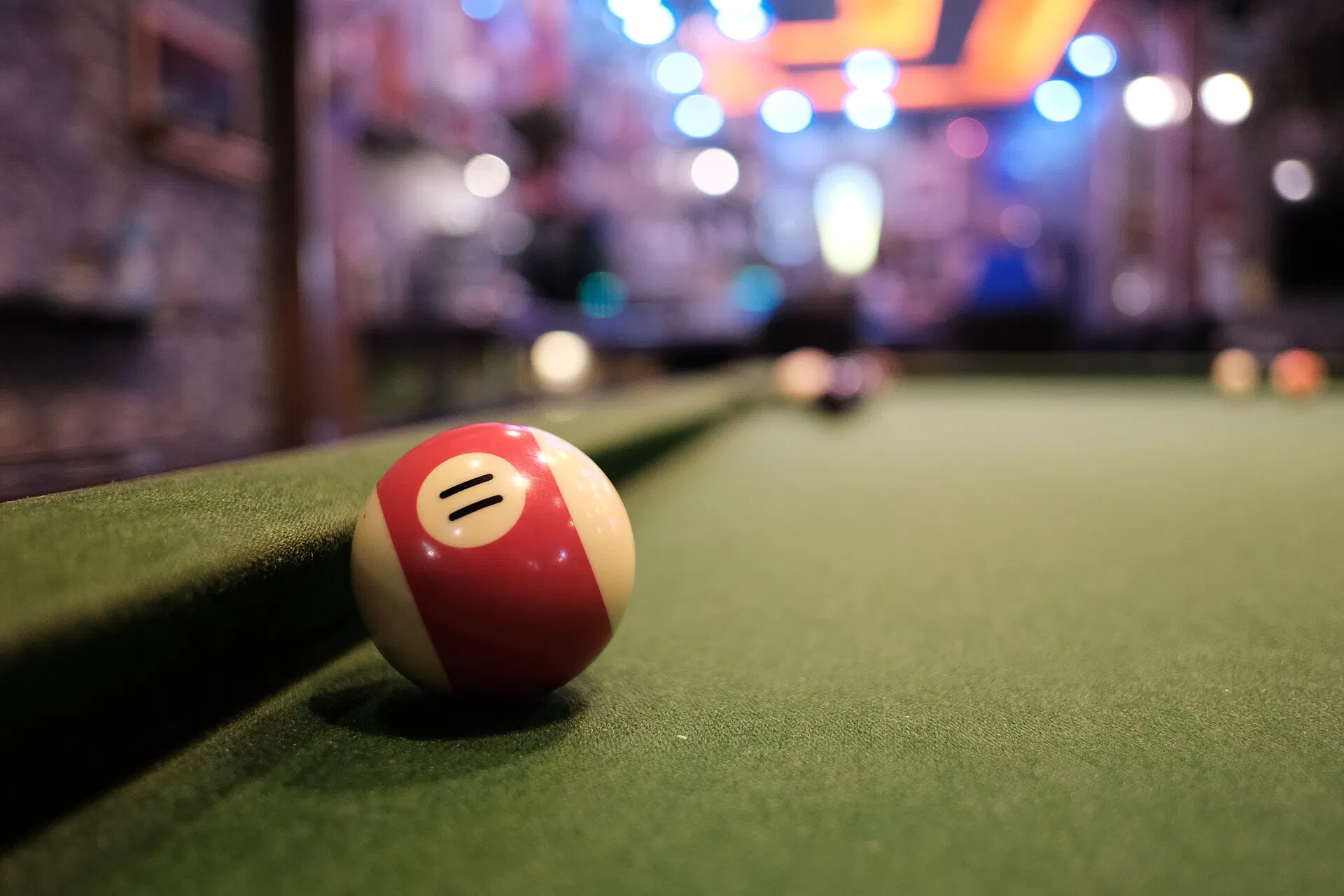 A striped ball on green felt under hall lights